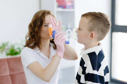 Niño usando inhalador con ayuda de profesional médico